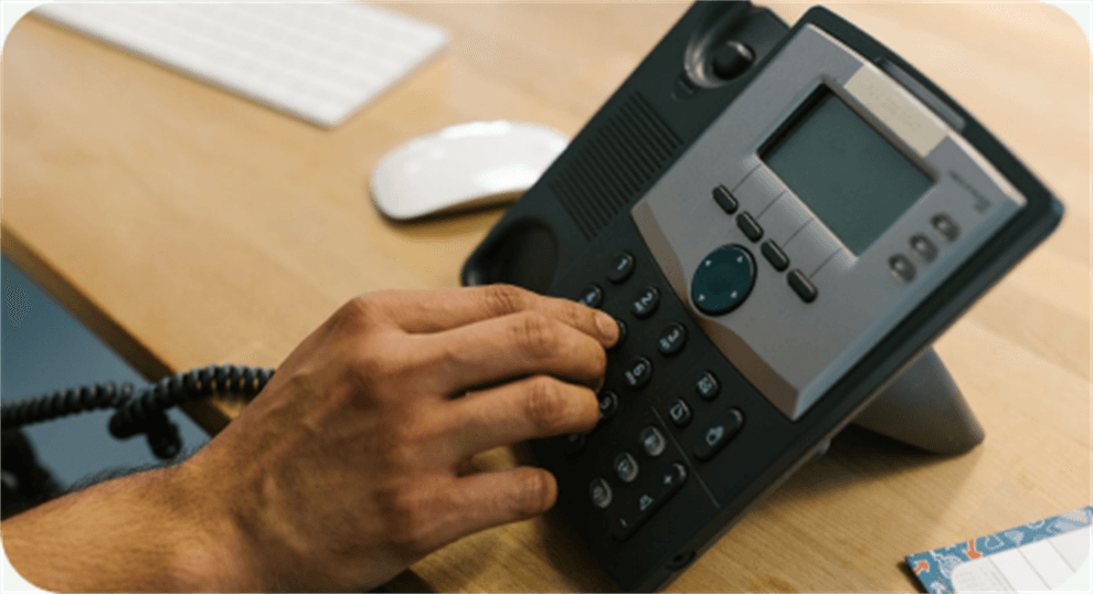 A business owner answering a desk phone at their workstation