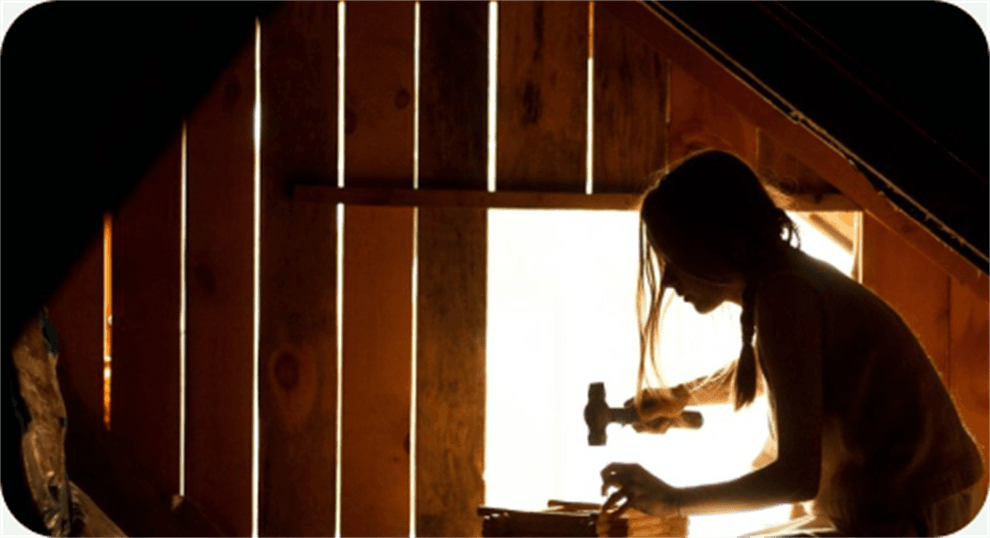 A maker working at a bench in a sunlit workshop