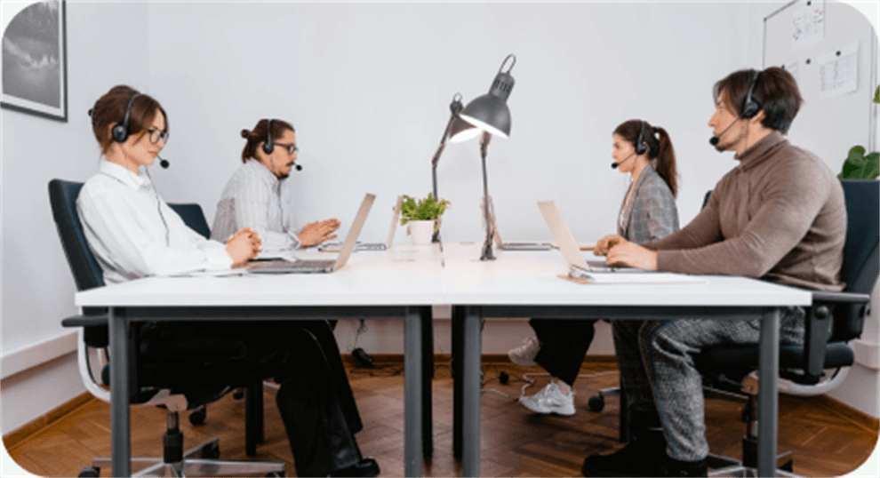 A support team wearing headsets around a shared desk
